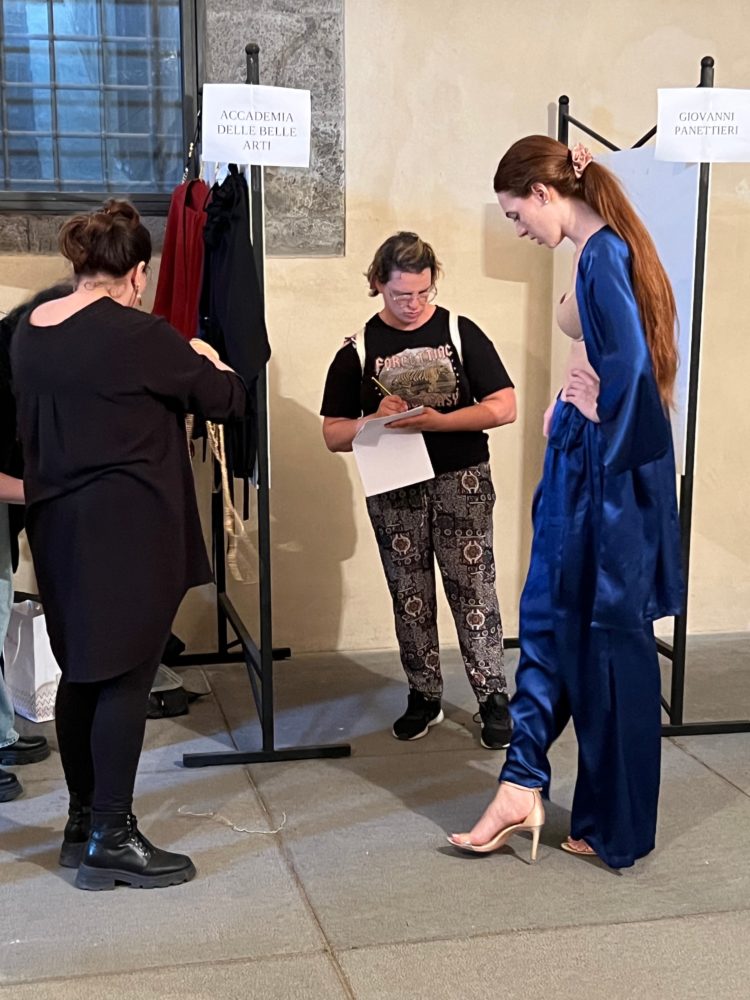 Fitting for the EVALab fashion show at Napoli Moda Design. In the center, Flora Feo, an employee of the EVA Cooperative, takes note of the details of the outfit chosen with Maddalena Marciano, back left.