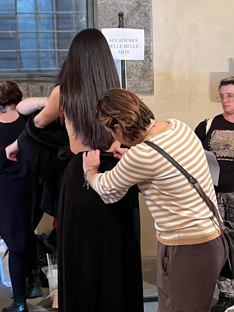 Daniela D'Addio, Vice President of the EVA cooperative and coordinator of the EVALab workshop, helps a model during the fitting for the fashion show at the Maschio Angioino in Naples on 10 June 2023.